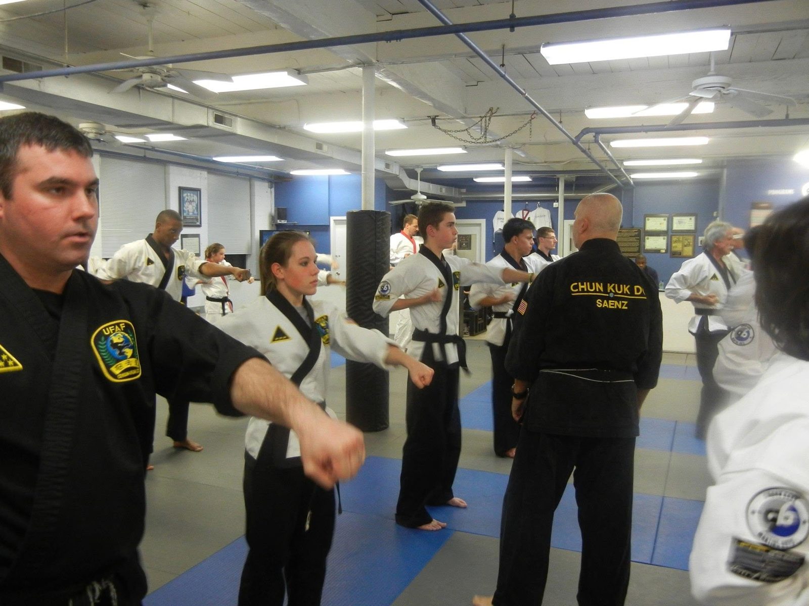 Black belt instructors leading a full class through punches on the Newtonville mat
